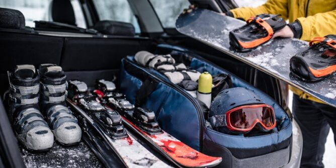 sprzęt sportowy zimą pakowany do bagażnika samochodu narty snowboard kask i buty przygotowane do transportu