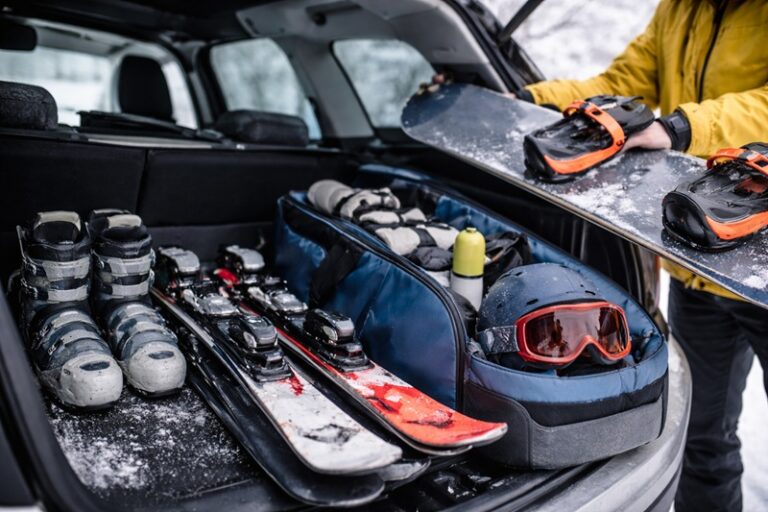 sprzęt sportowy zimą pakowany do bagażnika samochodu narty snowboard kask i buty przygotowane do transportu