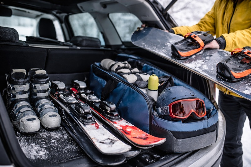 sprzęt sportowy zimą pakowany do bagażnika samochodu narty snowboard kask i buty przygotowane do transportu