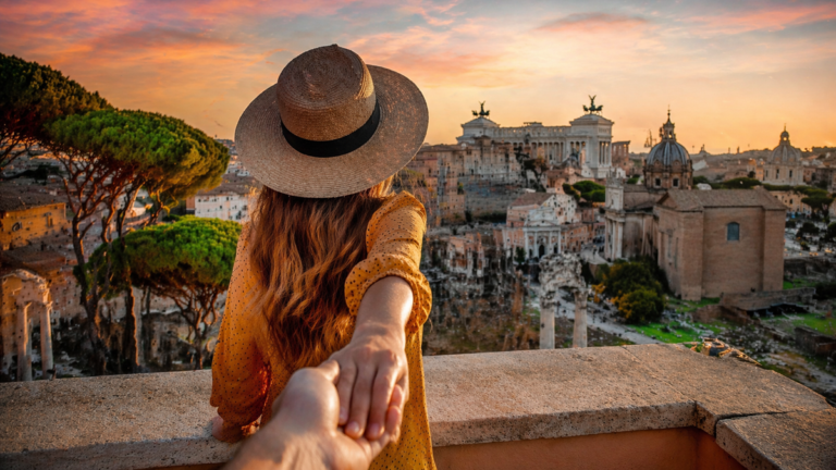 kobieta trzymająca za rękę na tle europejskiego miasta o zachodzie słońca, romantyczny weekend za granicą